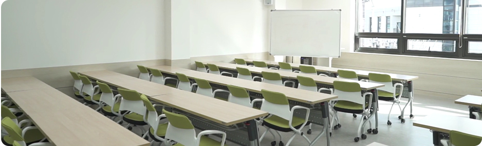 앞에는 프레젠테이션을 볼 수 있고 책상과 의자가 가득한 강당 사진